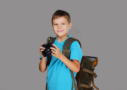 学龄前男孩用专业摄影机拍照与灰色背景隔图片