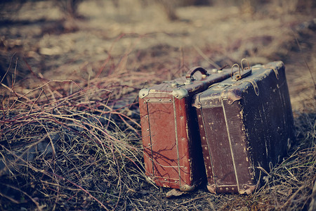 两个破旧的手提箱被遗忘在路上在一片图片
