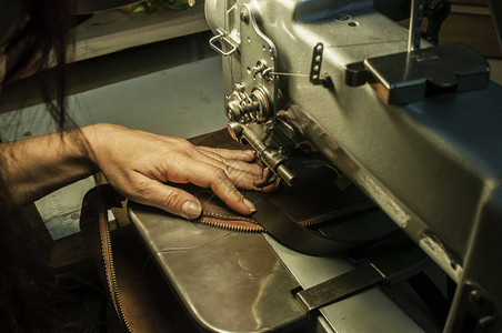 女裁缝的手将缝纫机缝制皮包袋紧闭作为工背景图片