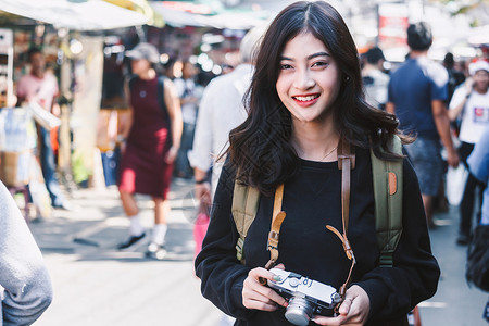 外出旅游的亚洲女游客拿着相机走在街头图片