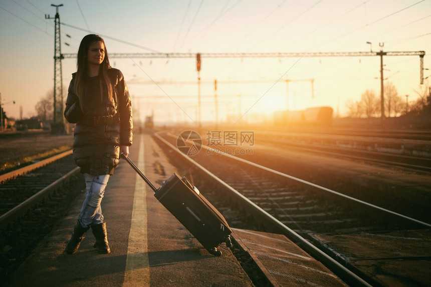 值日落时带行李在铁路上搭车的图片