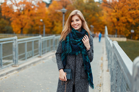 秋天带着围巾和围巾穿着时装大衣的笑容美丽图片