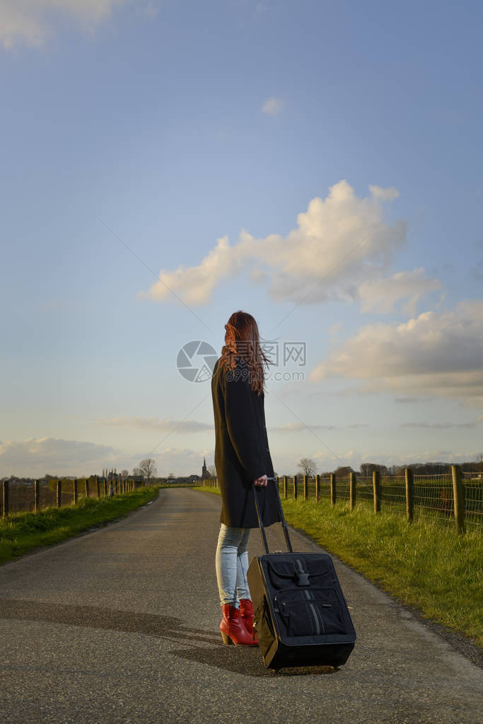 离家出走的女孩在路上拿着手提箱站着图片