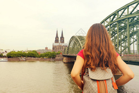 长头发和背包的年轻女旅行者享受着德国科隆大教堂和大桥的风景图片