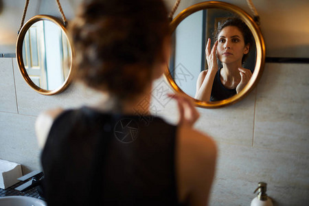 年轻美女照着镜子在厕所里刷新背景图片