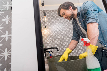 在洗手间橡胶手套清洗槽中英俊男图片