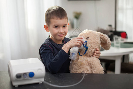 带吸入器的小男孩Nembulizer对玩具兔子做手术在家吸入是为了咳图片