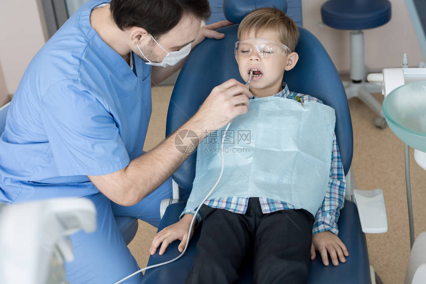 现代诊所牙医治疗牙齿和填充蛀牙时坐在牙科椅上的可爱图片