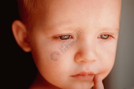 小孩提东西不开心的小可爱婴儿泪流满面小宝在哭小男孩子带着悲伤的脸他是背景