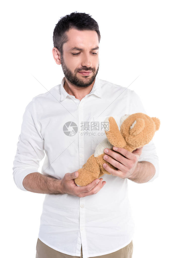 一个年轻的大胡子男抱着一只泰迪熊的半身照图片
