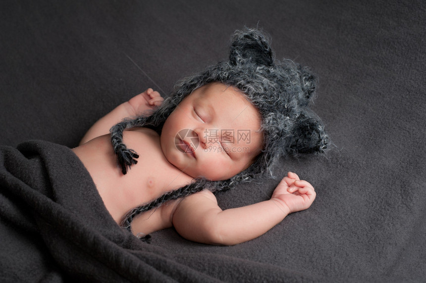 三周大的新生男婴戴着灰色钩编狼帽他睡在图片