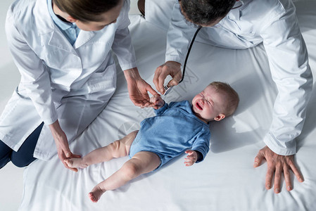 试图检查哭泣婴儿呼吸的儿科医生的高图片