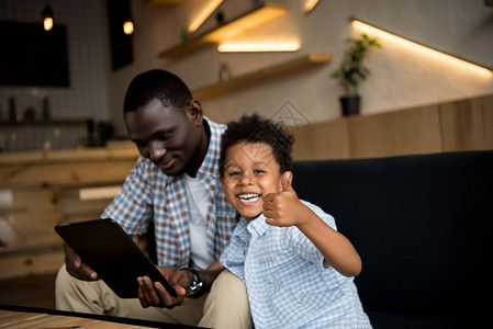 非裔美国父亲使用数码平板电脑而可爱笑的图片