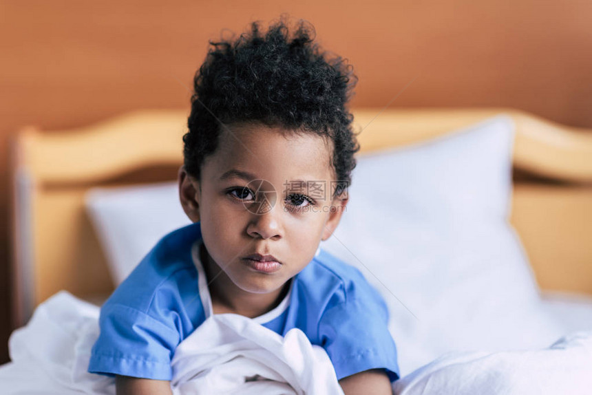 严重非裔美国小男孩在诊所床上看照相机时有选择地关注重图片