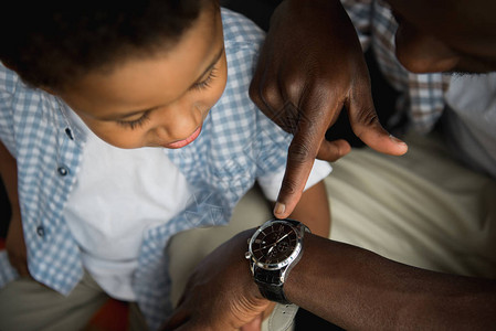 美国父亲和儿子一起检查手表的非洲父子拍图片