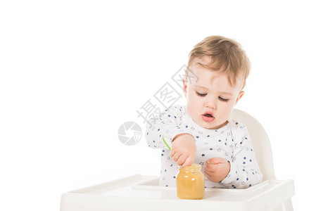 小男孩吃罐子里的纯净食物坐在高椅子上孤图片