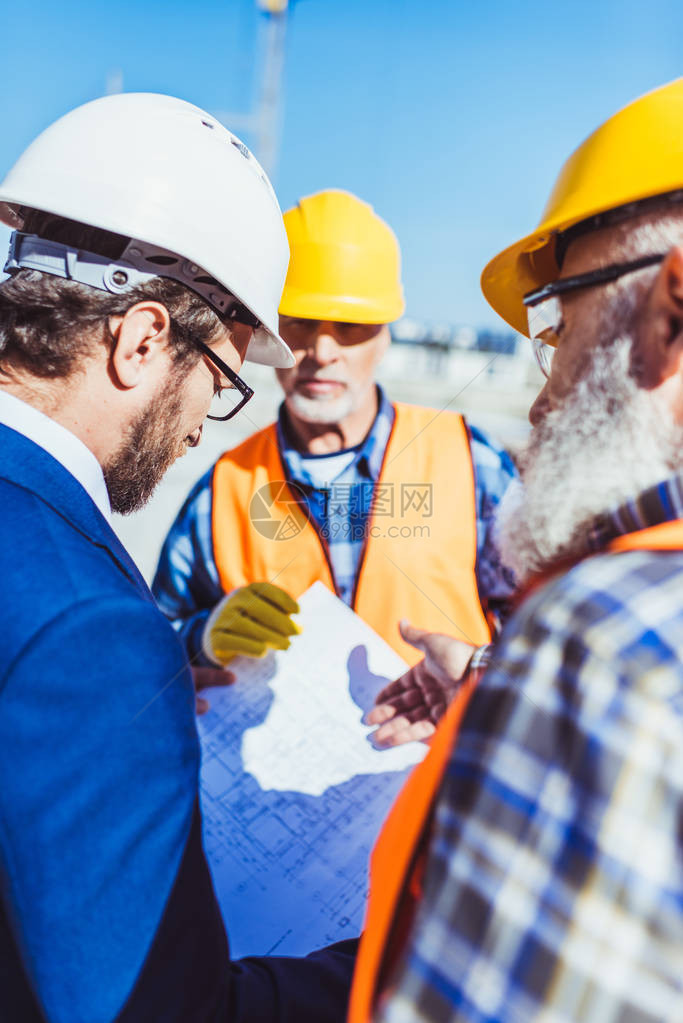 身着防护服的工人在建筑工地与商人图片