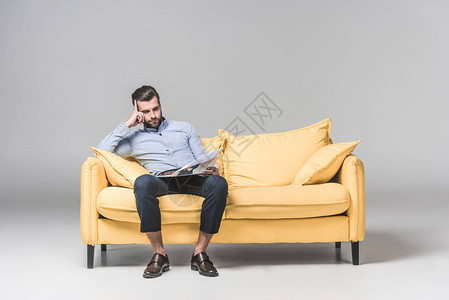商人坐在灰色的黄色沙发上看图片