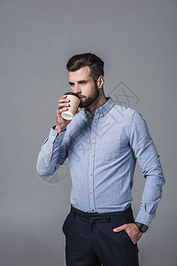 高雅的时尚商人喝着一次咖啡杯里的咖啡图片