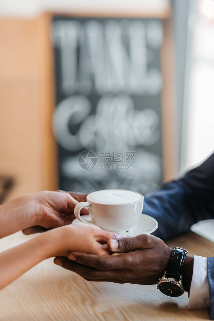 女服务员给咖啡店的非裔美国商人喝杯咖啡的景象图片