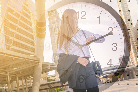现代城市中女商人的双重曝光与时钟作为背景图片