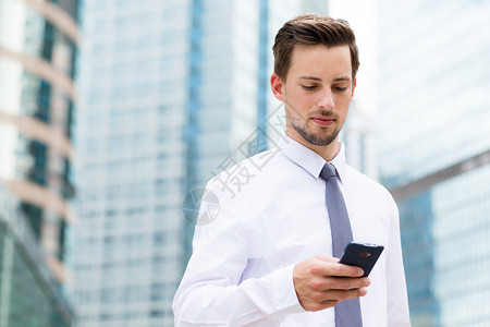 白人商在户外用智能手机穿白衬衫图片