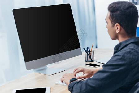 青年商人使用台式计算机办公室内空白屏背景图片