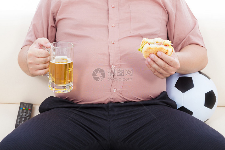胖商人吃食物和啤酒坐在沙发上图片