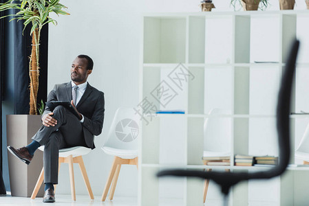 坐在办公室的椅子上望着远处的非洲商人图片