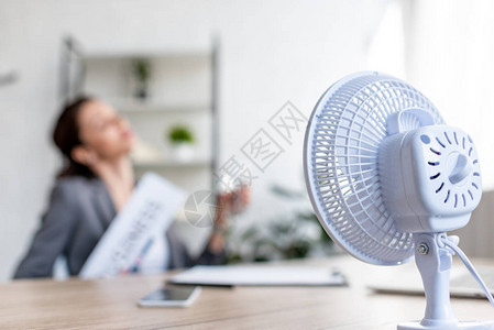 商业妇女坐在电扇附近时遭受炎热的有选择图片