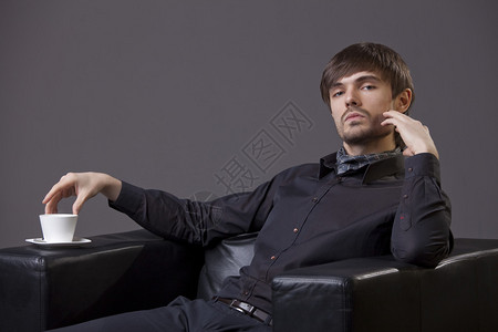 时装男坐在椅子上喝图片