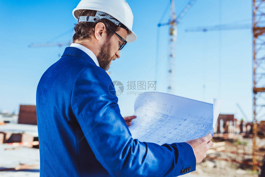 Hardhat的商人和检查建筑工地建筑计划图片