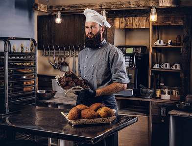面包店促销英俊的大胡子厨师穿着制服在面包店的厨房里展示一背景图片