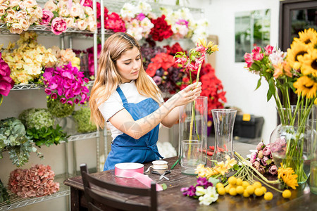 漂亮的西班牙女花店女花商在她工作间安排花朵背景图片