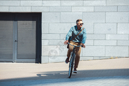 穿着太阳眼镜的时尚中年男子骑自行车图片