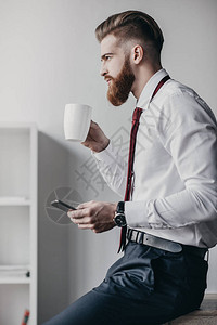 使用智能手机和办公室喝咖啡的图片
