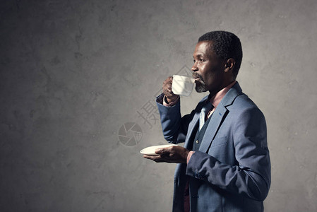 成熟的非洲裔美国人从杯子里喝咖啡图片
