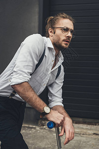 戴眼镜的时髦胡子青年男子站立在摩托图片