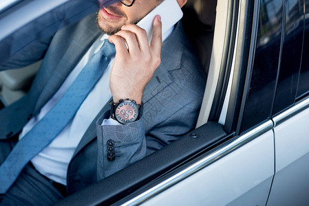 商人在驾驶汽车时使用智能电话交谈的图片