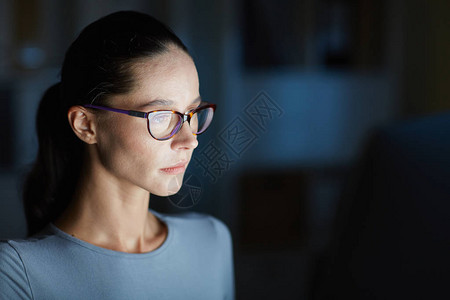 夜间在办公室值班时阅读在线数据的女孩头目眼镜图片