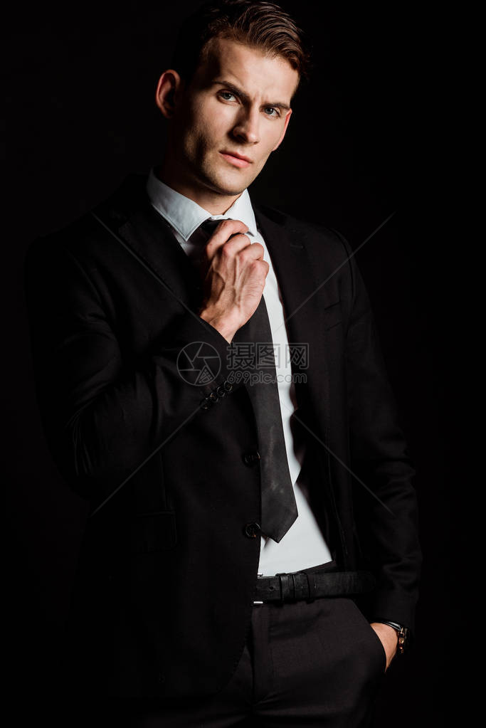 英俊的商人男子摸领带手站在口袋中在图片