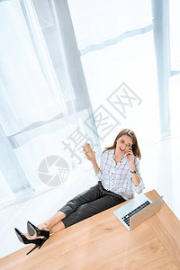 坐在椅子上与笔记本电脑对着桌上的双腿坐在图片