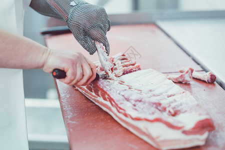 屠夫在屠宰场用刀切肉以进行一步加工图片
