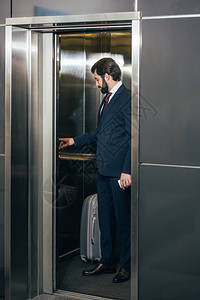 电梯内带行李按钮的商人图片