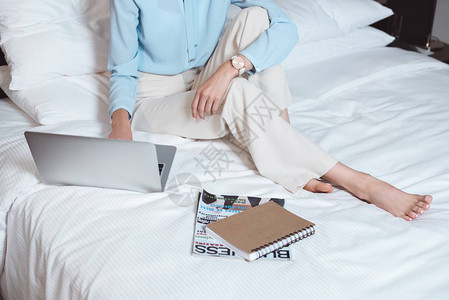 在旅馆房间床上使用笔记本电脑的青年赤脚图片
