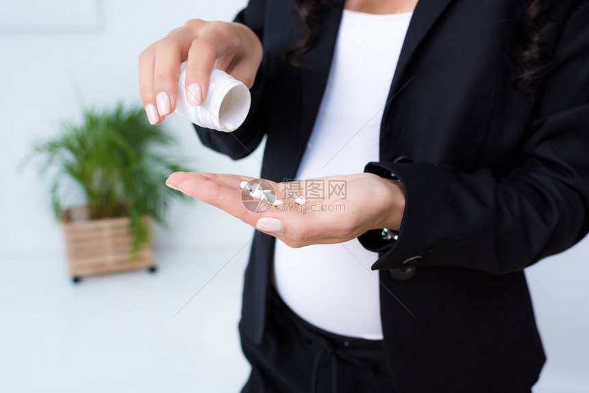 手里拿着一堆药丸的怀孕女商人的镜头图片