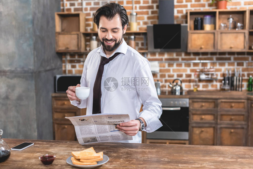 拥有咖啡杯和厨房阅读报纸的英俊独行图片