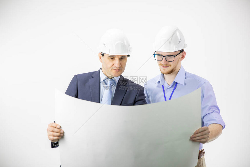工程师和建筑师戴着硬质安全帽工作开会讨论设计规划测量在白色背景上隔离的建筑蓝图的布局BI图片