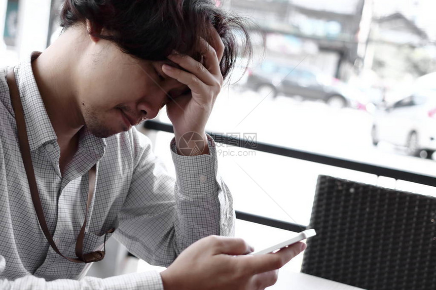 忧心忡的亚洲年轻商人在寻找手机智能手机焦虑的商业图片
