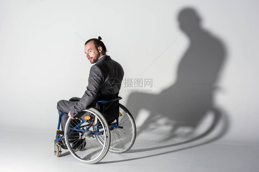 坐在轮椅上墙上有影子的年轻残疾青年个体图片